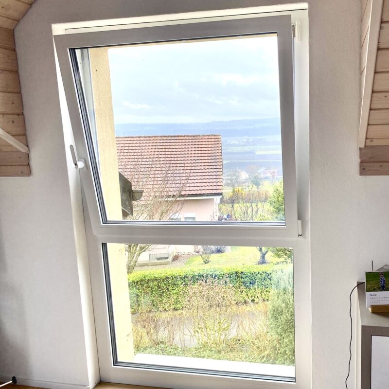 Fenêtre ouverte avec vue sur jardin et toits